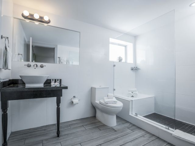 A clean and modern bathroom with a black vanity, white sink, toilet, and shower.