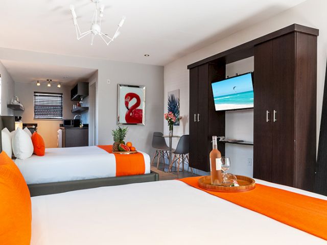 A hotel room with two beds, a TV, and a small dining area